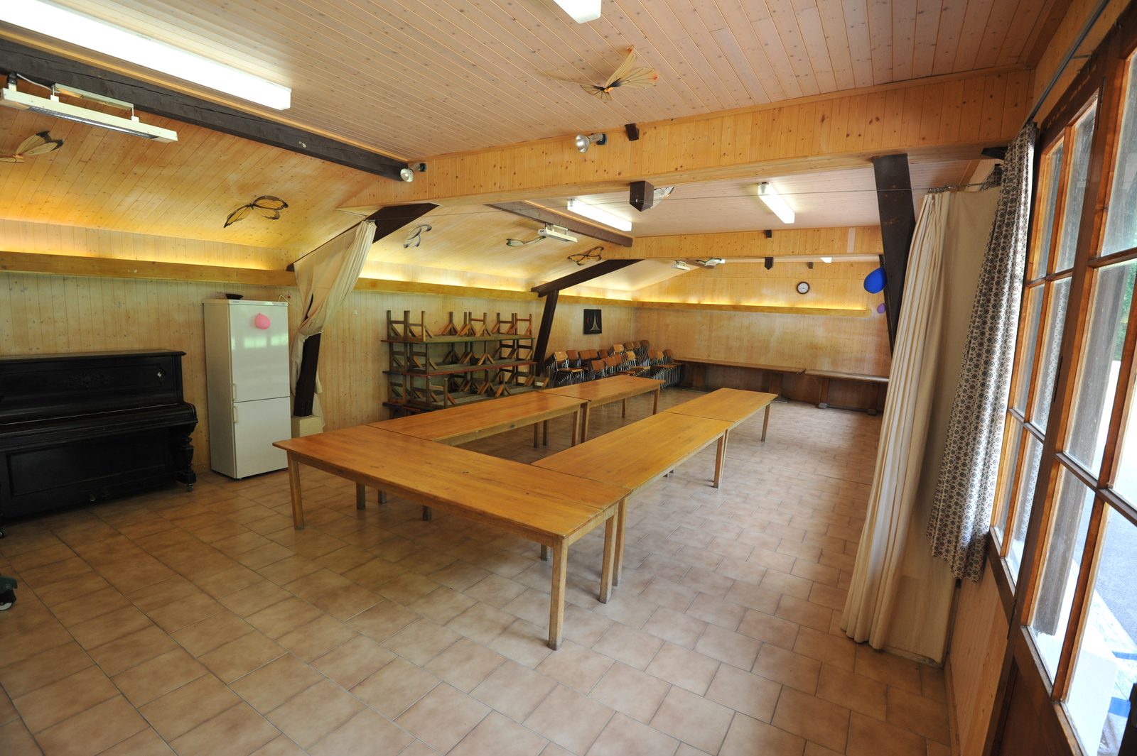 L'intérieur de la salle des fêtes « Les Cytises », tables dressées